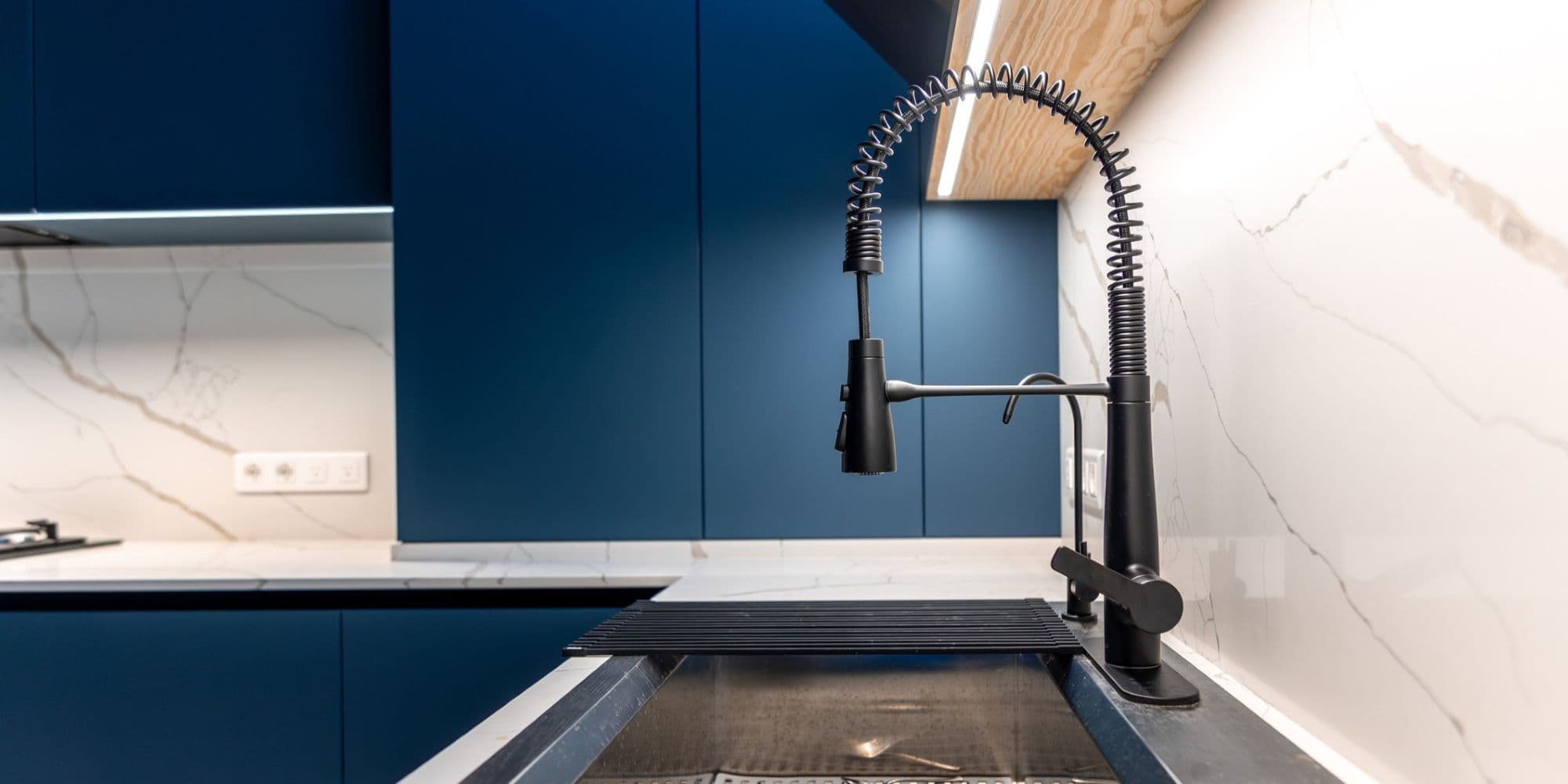 Wide view of a kitchen sink area with a black faucet in Scandinavian-inspired design. Aesthetic blend of marble, wood, and functionality.